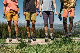 A group of friends stand at the top of red cub trail with the Taylor Hilgard Mountains behind sporting the newest collection of Curious Creatures Shorts & Tops