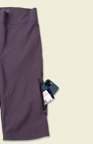 A phone and wallet peek out of the side pock of a pair of purple Marilyn Shorts