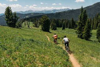 Hillary and Hannah rip downhill across a beautiful Montana meadow vista through spindly pines and hot temps