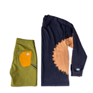Avacado green bike shorts with yellow pocket lay down next to black longsleeve tee with brown tie dye circle burst. Curious Creatures googly eyes logo
