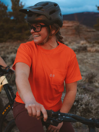 Madeline wearing a paintbrush red shirt and helmet on a bike in a natural setting