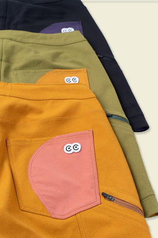 White eye logo woven patch labels pop out on a multi color display of the various Ramble Scramble shorts rear pockets