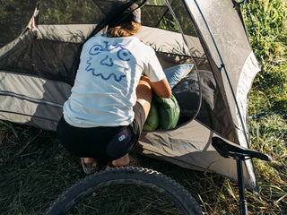 Rachel putting her tent together at Red Cub Trailhead wearing the White Bikeface Tee