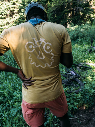 Chima taking a break on the climb up red cub canyon in Montana wearing the Bikeface Faded Mustard Tee