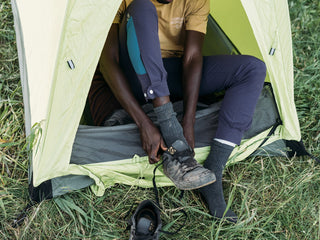 Chima takes his worn out 5.10 riding shoes off before getting into his tent wearing purple pants