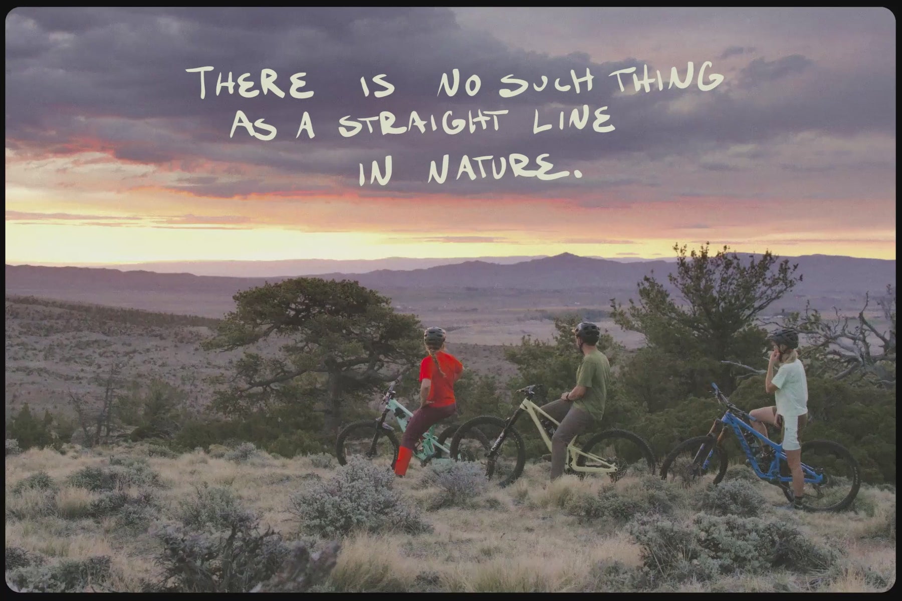 Video of three mountain bikers watching the sunset with hand written text 'There is no such thing as a straight line in nature.'
