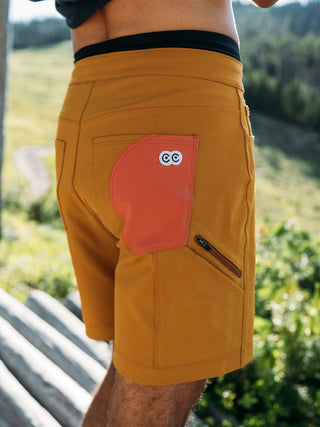 Rear view on model of the buckthorn brown shorts displaying the circular color block in pink and bright white eyes logo
