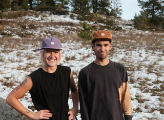 Sophie and Pasha hang out in the snow wearing all black with colorful curious eye logo hats
