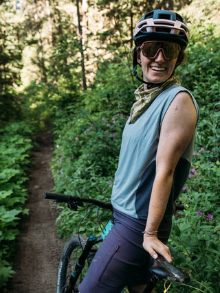 Hannah takes a moment on the trail to wait up for friends on her mountain bike wearing a steel blue tank