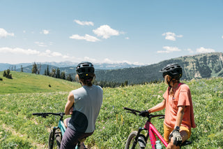 Hannah and Hillary soak up the view on their bikes of Yellowstone National Park in the distance with their Curious Creatures tank and pocket tee on